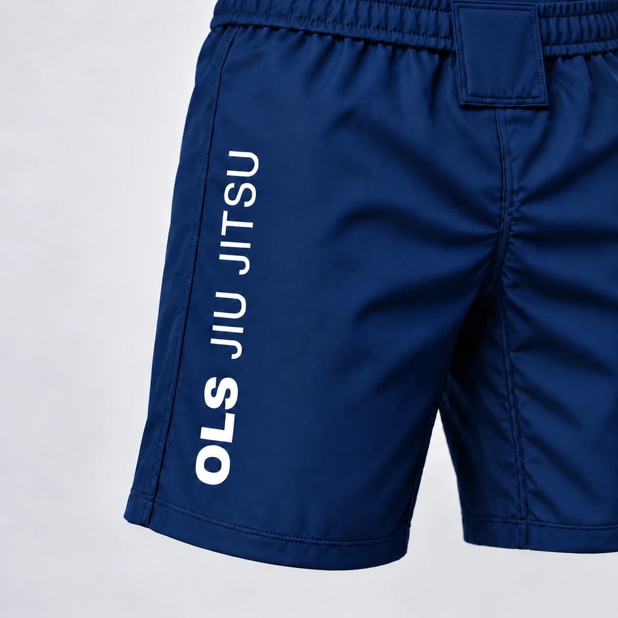 O cós e a assinatura OLS JIU JITSU na lateral da Bermuda OLS azul